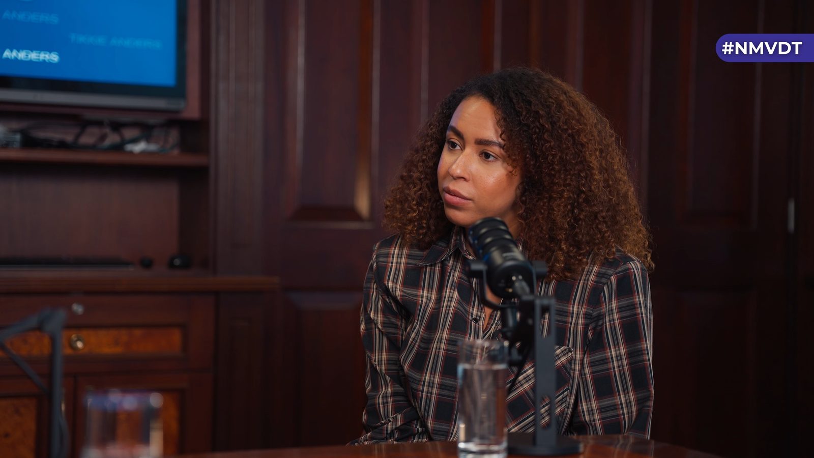 Podcastgast in gesprek in een luxe vergaderzaal op kantoor, met houten lambrisering.